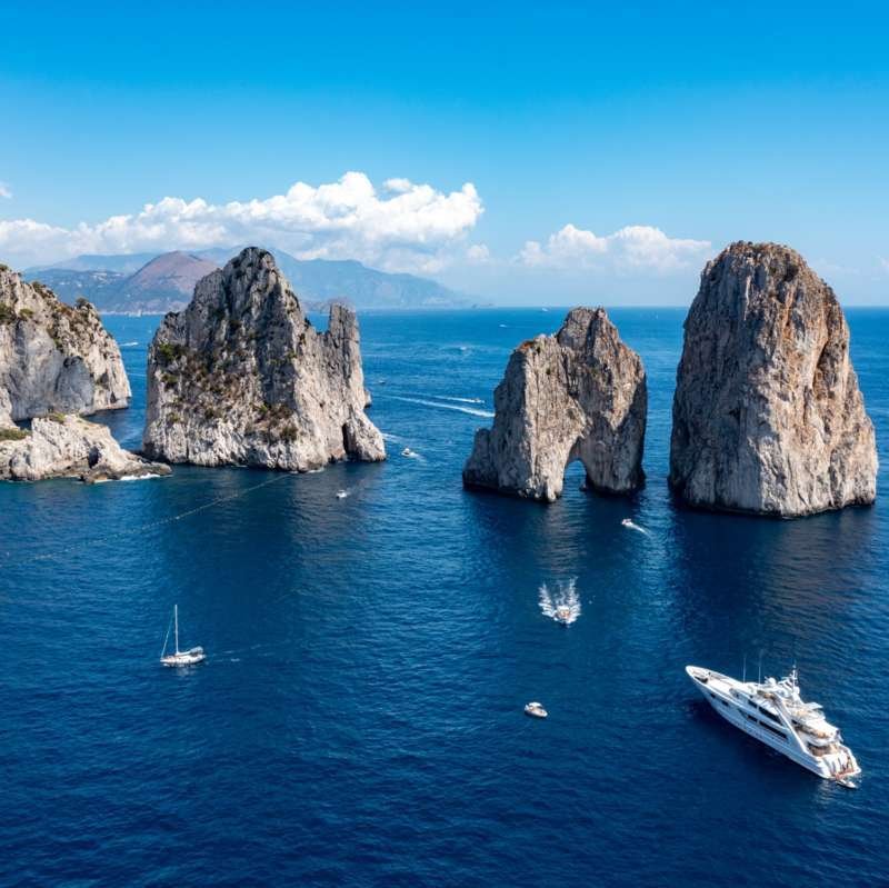 Boat tour passing the three Faraglioni rock stacks off the coast of Capri