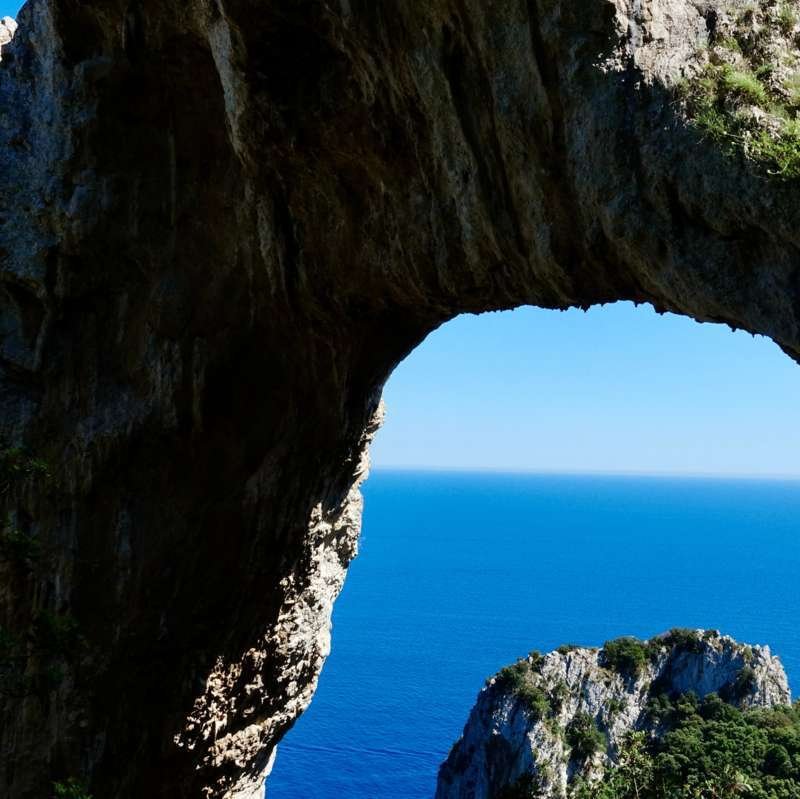 Deep blue Mediterranean sea framed by the natural rock arch of Capri